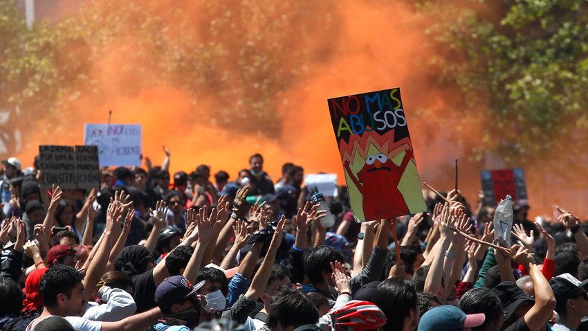 SANTIAGO, CHILE - OCTOBER 21: Demonstrators display flags and banners during a protest against President Sebastian Piñera on October 21, 2019 in Santiago, Chile. President Sebastian Piñera suspended the 3.5% subway fare hike and declared the state of emergency for the first time since the return of democracy in 1990. Protests had begun on Friday and developed into looting and arson, generating chaos in Santiago, Valparaiso and a dozen other cities resulting in at least 8 dead.  (Photo by Marcelo Hernandez/Getty Images)