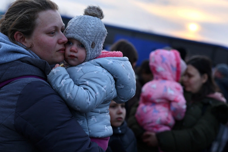 Ukrainian women fleeing Ukraine, hold their children as they arrive at a temporary camp in Przemysl, Poland on March 1, 2022 [Kai Pfaffenbach/Reuters]