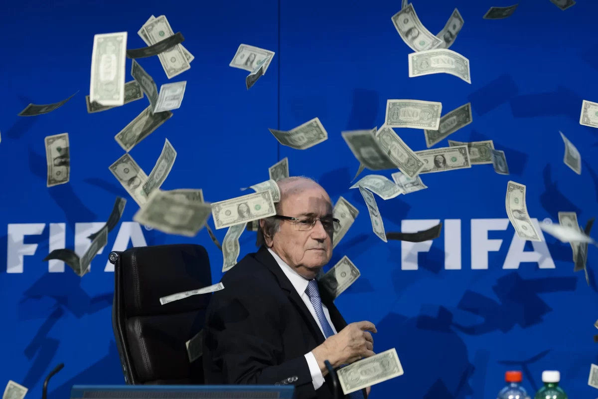 In 2015, FIFA President Sepp Blatter was thrown fake dollars by a protester during a press conference. Image credits: Getty Images